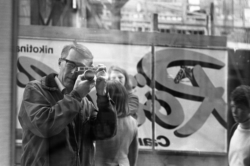 Man spiegelt sich im Schaufenster wie er ein Foto macht