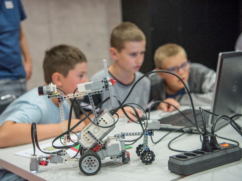 3 Kinder programmieren einen Lego-Roboter