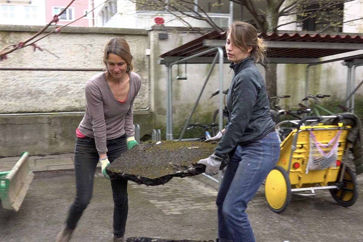 Weg mit dem Belag!, auch wenn manchmal zu zweit angepackt werden muss, um den Asphalt zu entsorgen und Platz zu schaffen für heimische Pflanzen (Isabella Sedivy und Sabrina Stettler)