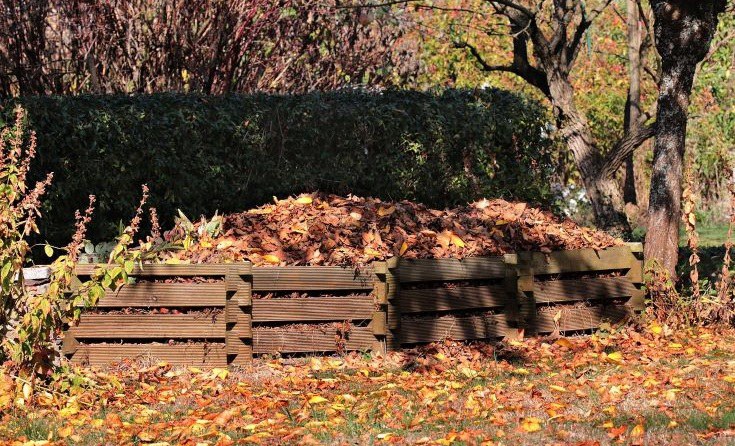 Komposthaufen mit buntem Laub überdeckt im Herbst